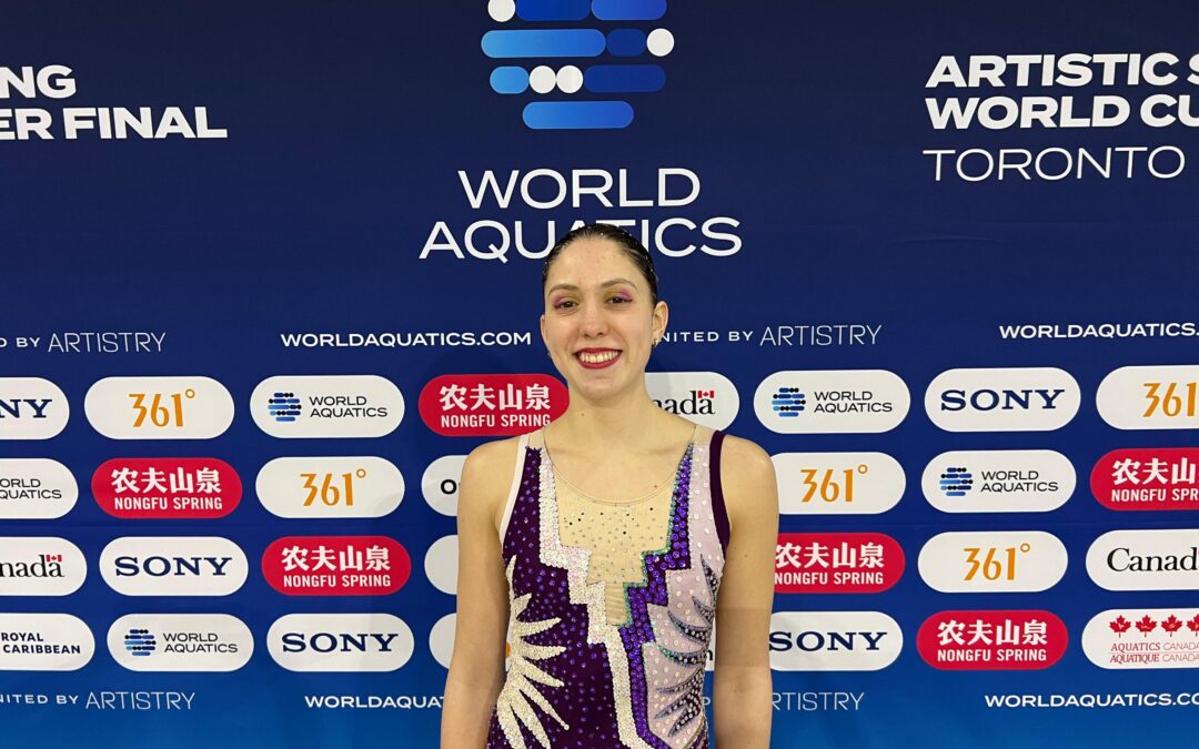 Tiziana Bonucci posa con su traje de competencia frente al backdrop oficial de la World Cup de Natación Artística en Toronto